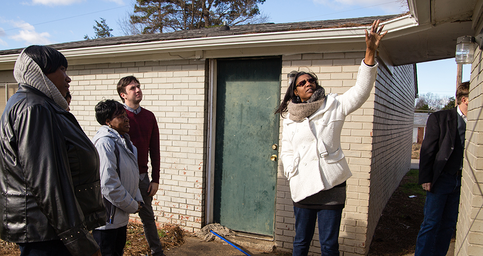 Josie Williams of the Greensboro Housing Coalition walks a group through the Cottage Grove neighborhood, pointing out issues that can lead to health problems. [Photo by Mike Dickens]
