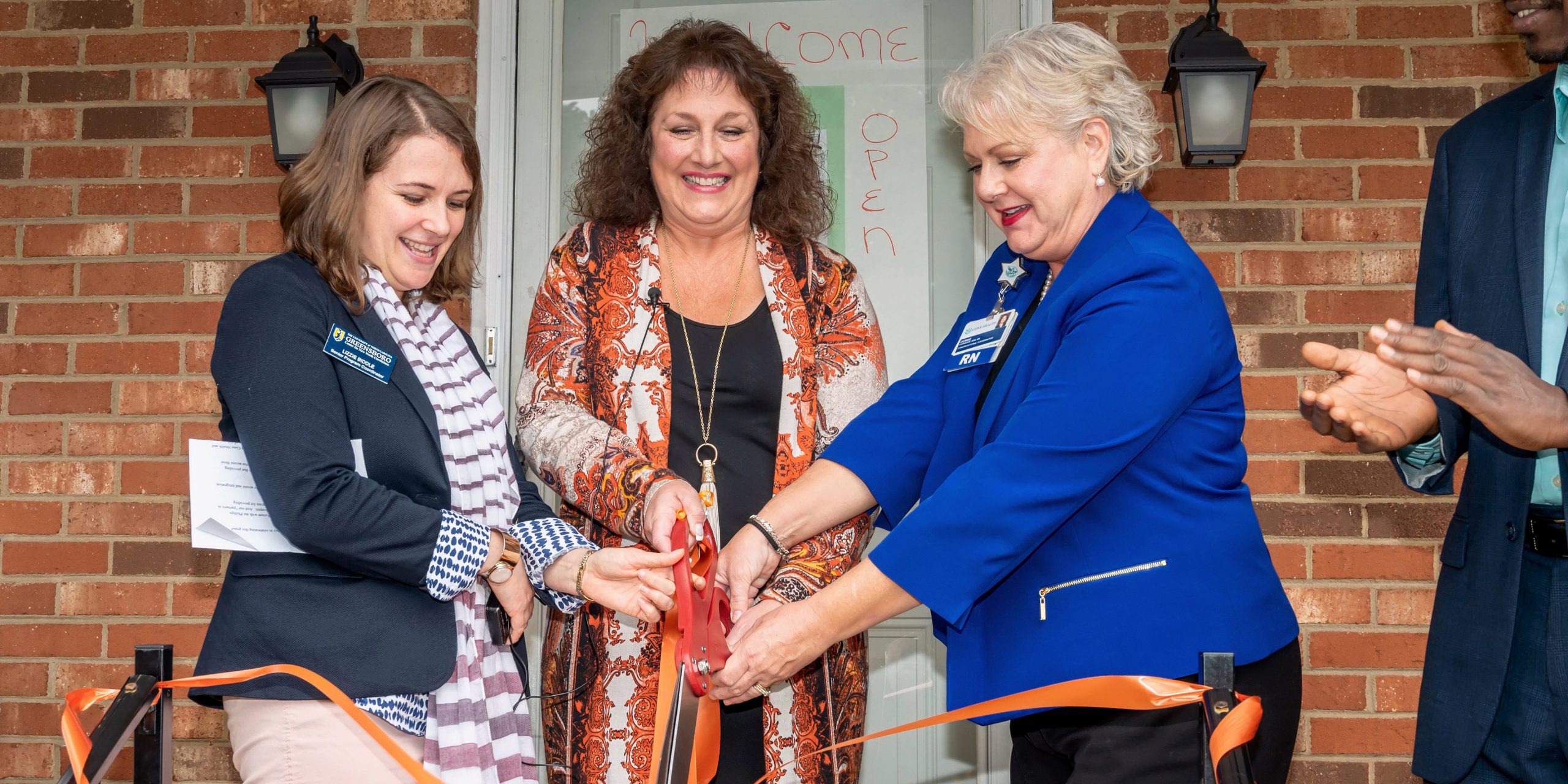 3 women cut a ribbon for a new community health center