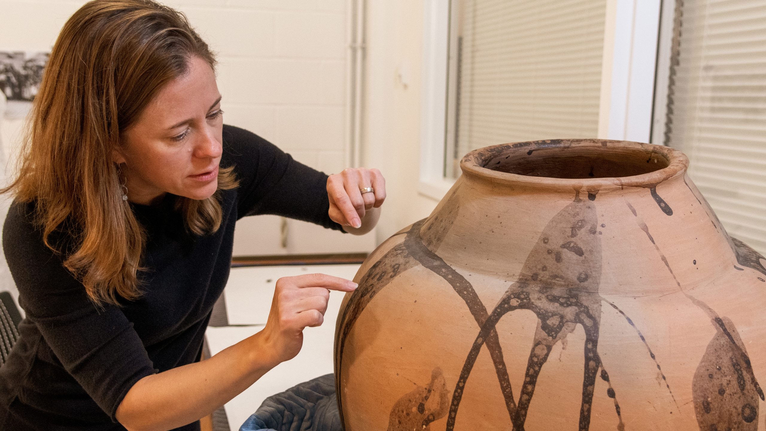 Dr. Elizabeth Perrill evaluating a piece of ceramics.