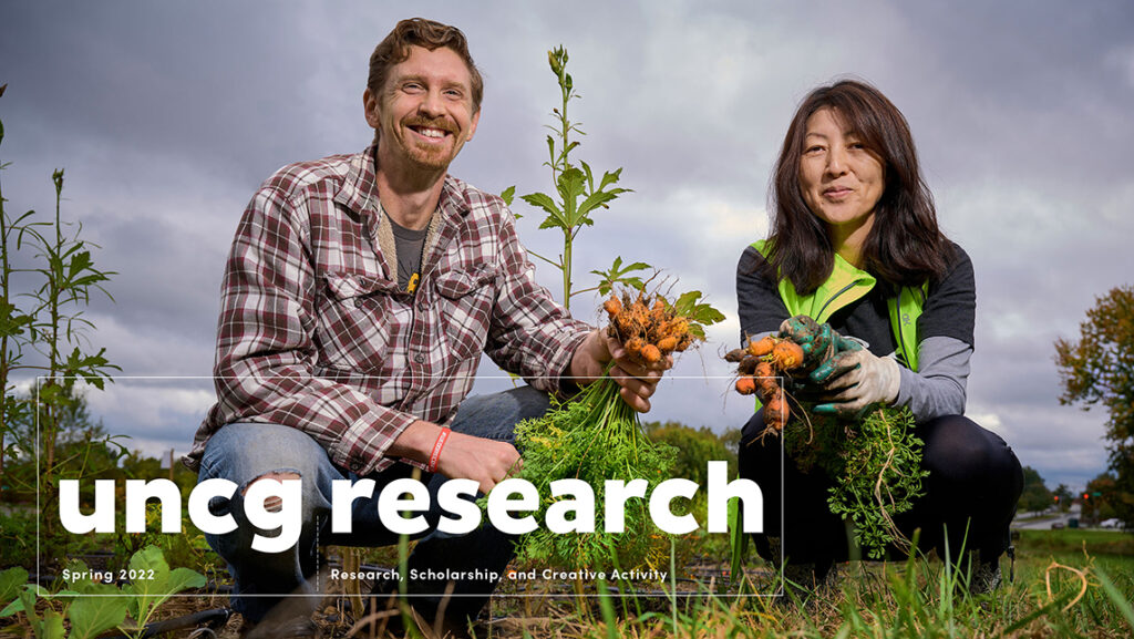 Nathan Lewis and Dr. Etsuko Kinefuchi holding freshly harvested carrots in the Garden of Peace.