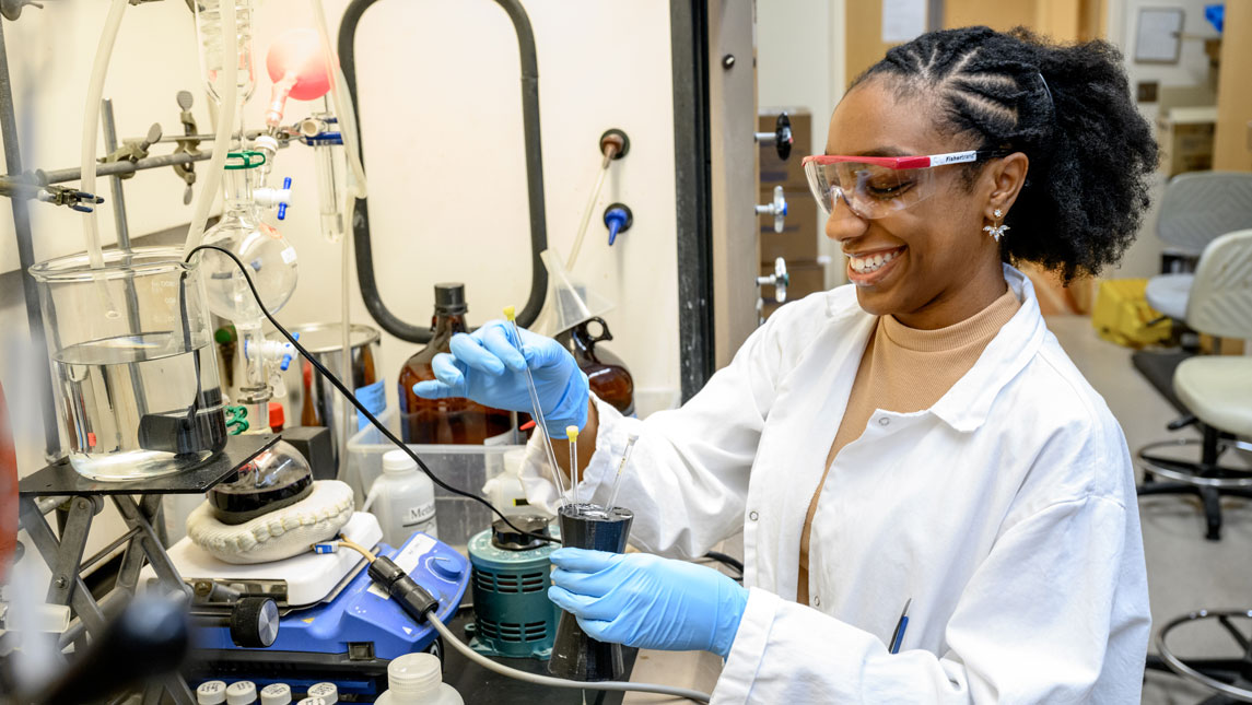 Masters student Tangela Johnson rearranges lab tools at a work bench. 