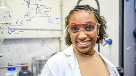 A portrait photo of Tangela Johnson in the lab in front of a whiteboard. 