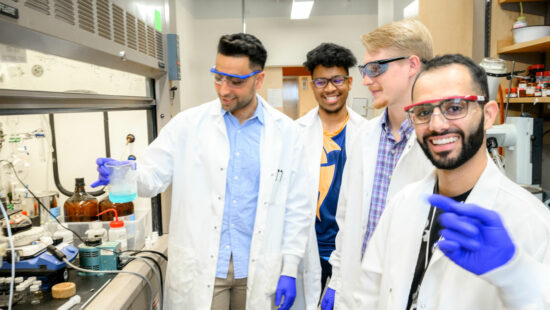 Abraham Ustoyev, Logan Brown, Philip West, and David Tanas stand together in the lab. 
