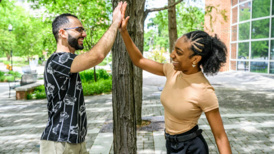 David Tanas and Tangela Johnson high-five outside of the Sullivan Science building.
