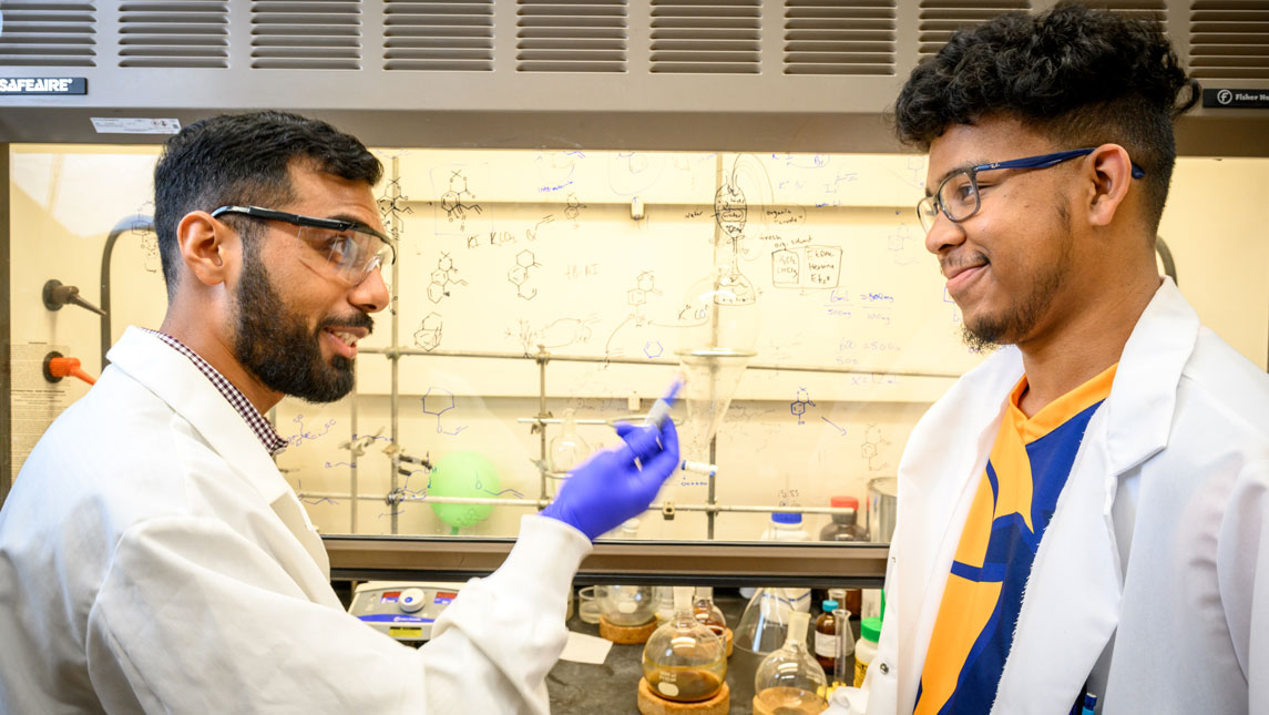 Students Harris Khan and Logan Brown mid-conversation in the lab.
