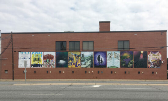 A series of paintings accompanied by cast sculptures and audio boxes hang on the outside of the brick IOB building. 