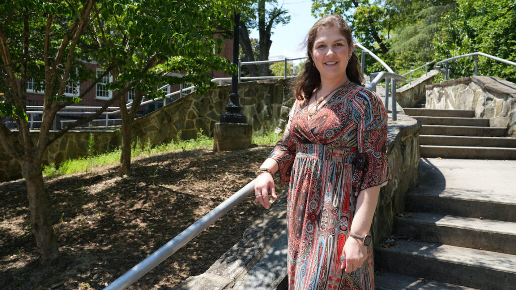 Woman poses outside with her arm resting on a stair bannister.