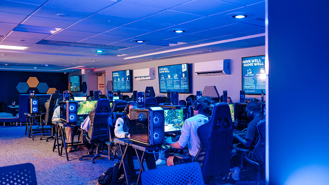 Students sitting at desktop computers playing video games in esports arena