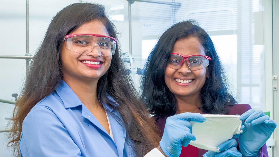 two female scientists in a lab holding a filter.