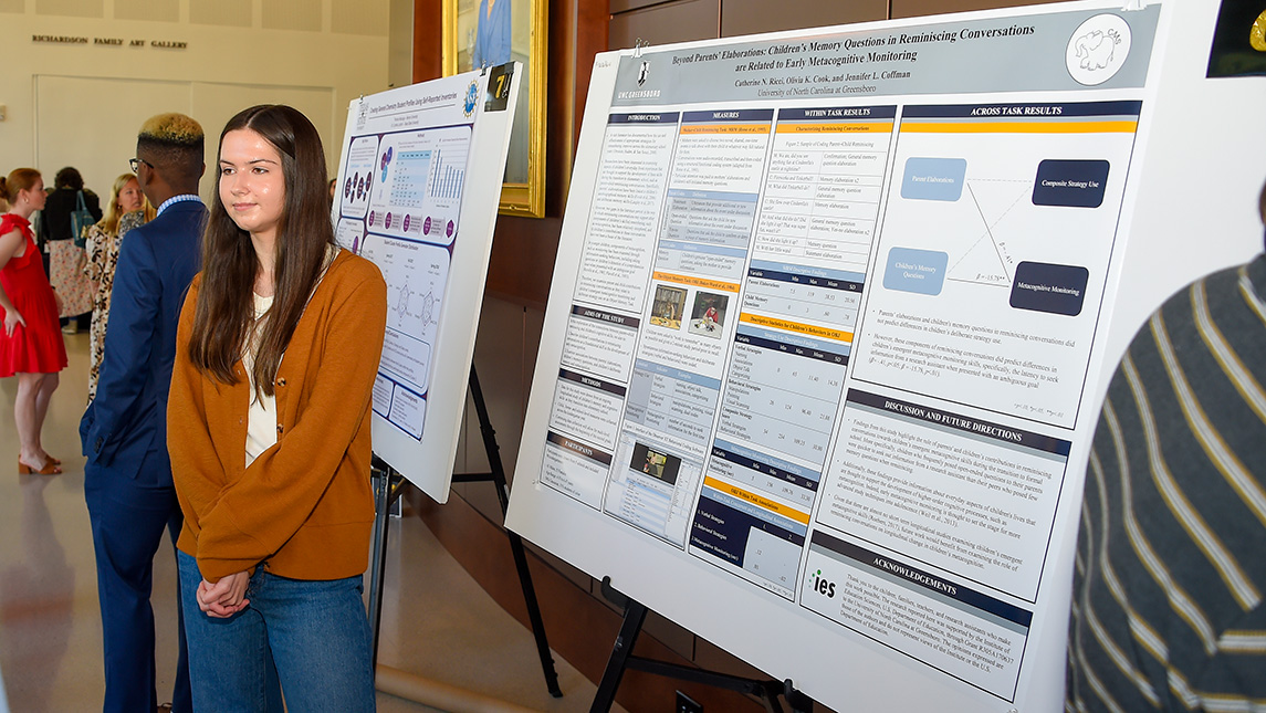 Student stands in front of research board at convention