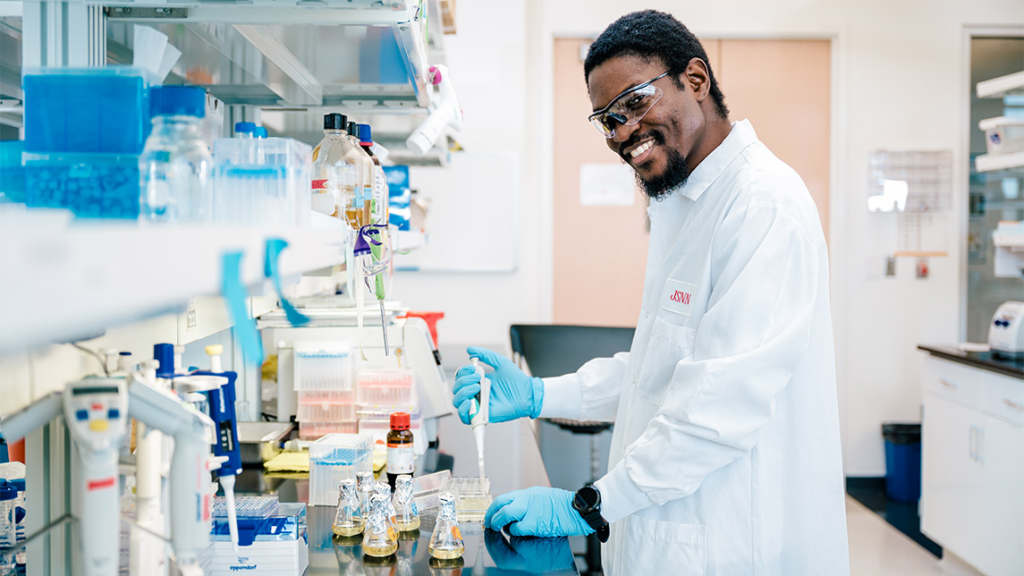 Scientist in lab smiling as he looks at the camera.