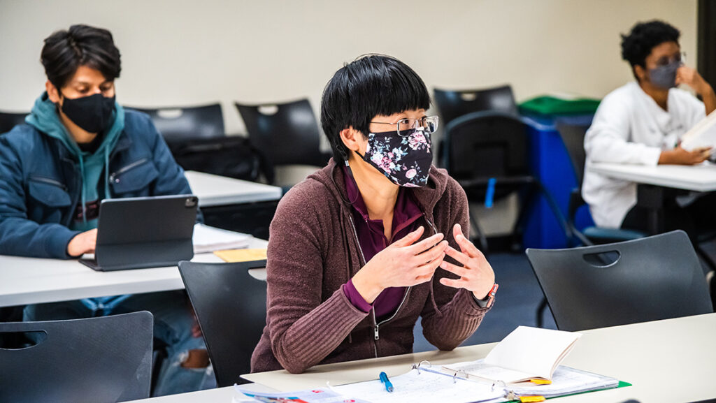 Masked students sit in a classroom.