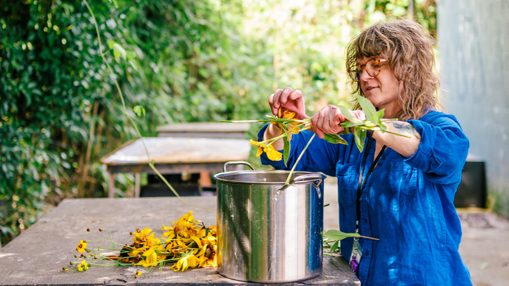 UNCG theatre lecturer's Tara Webb cutting flowers over a metal pot
