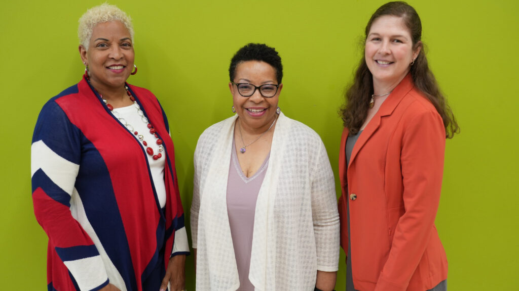 UNCG School of Nursing faculty posing in front of green wall
