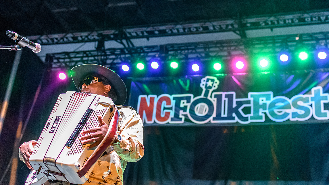 A musician playing the accordion on stage at NC Folkfest
