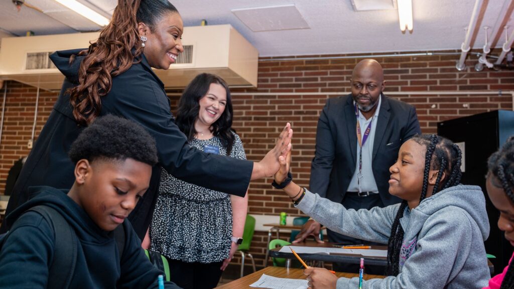 Grad student tutor high fiving a student while others watch