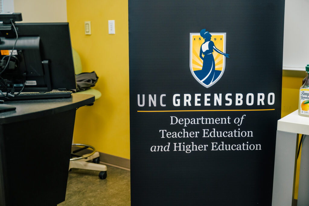 Navy blue banner with UNCG Department of Teacher Education and Higher Education logo