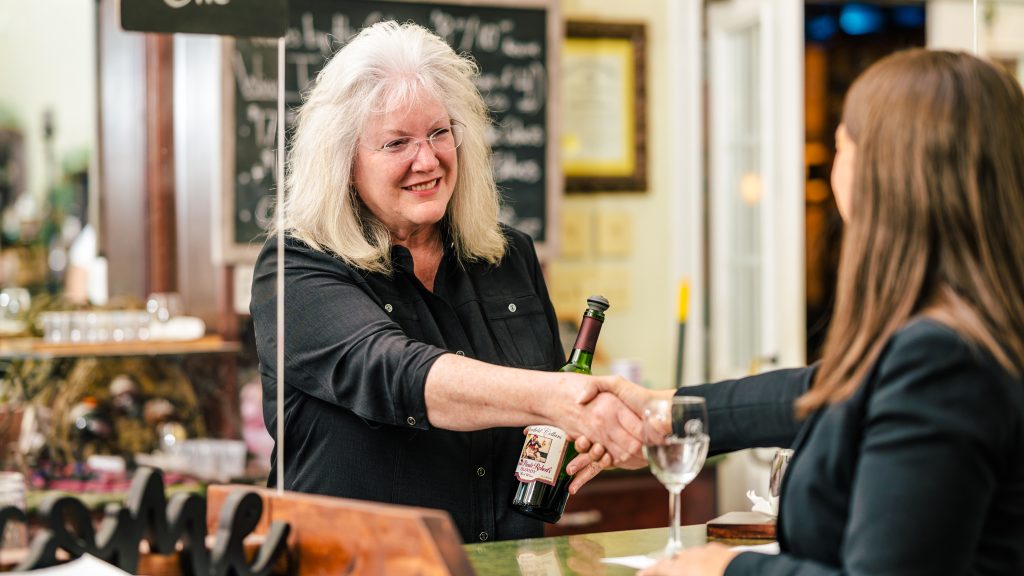 A woman shakes hands with a UNCG student doing research about agritourism