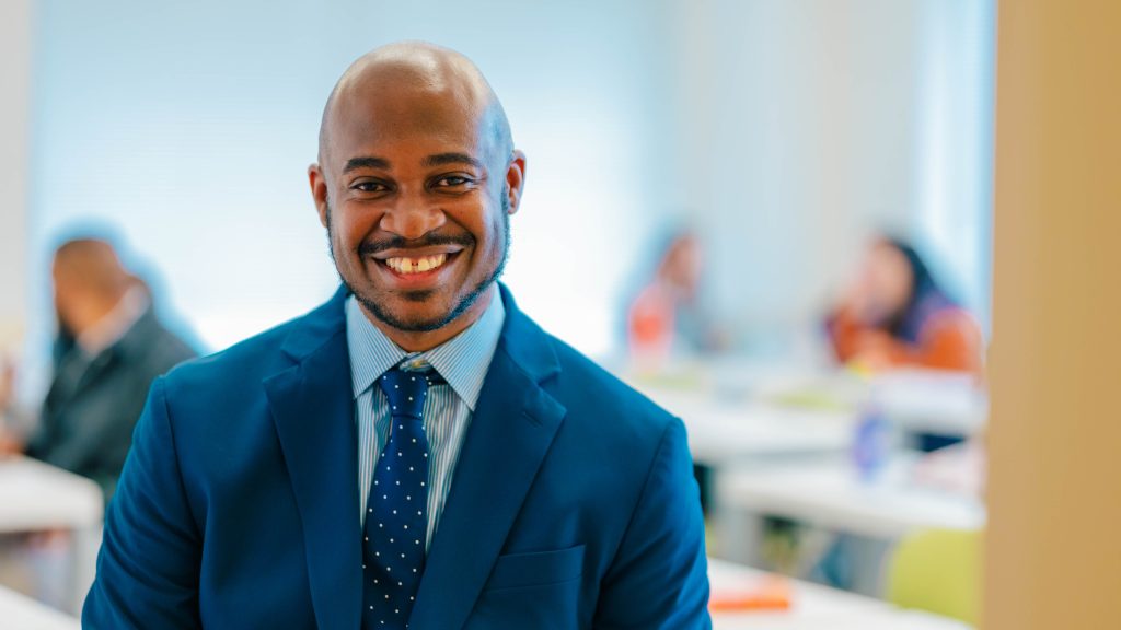 UNCG SOE professor Dr. Jesse Ford stands in front of his class and smiles