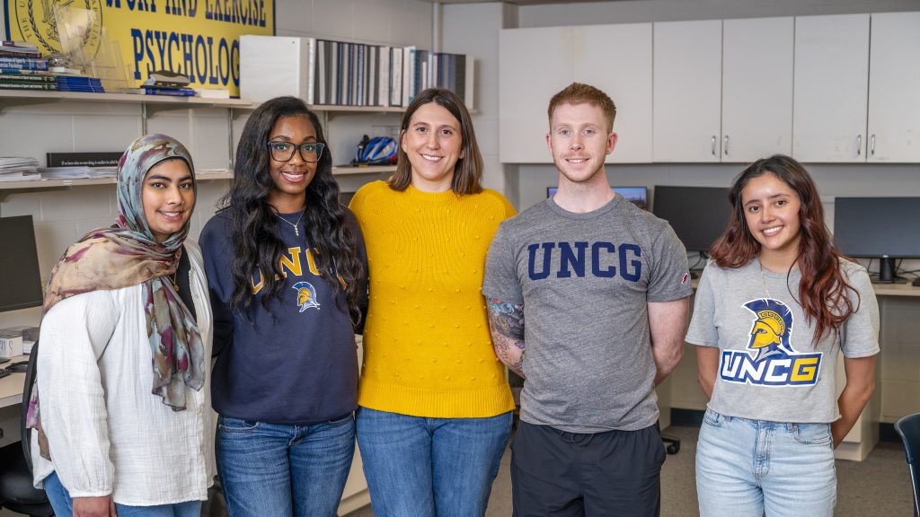 Dr. Jaclyn Maher in yellow poses with undergraduate students