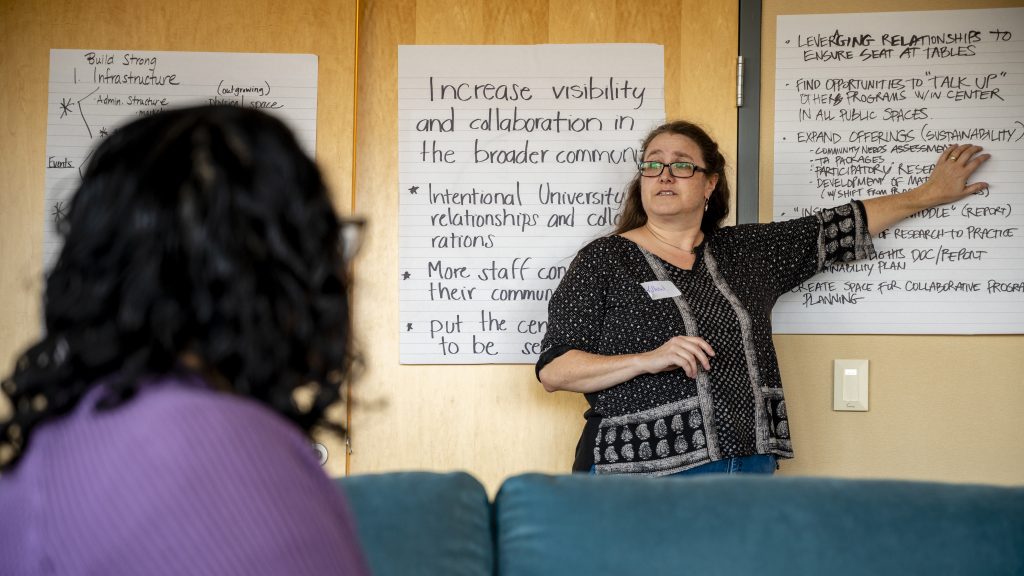 Willow Burgess-Johnson leads a meeting while pointing at a poster
