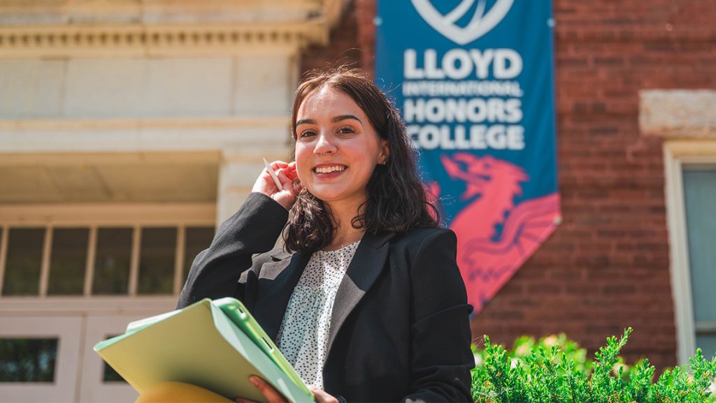 Honors College graduate Natalia Fagundez stands in front of the Lloyd International Honors College building