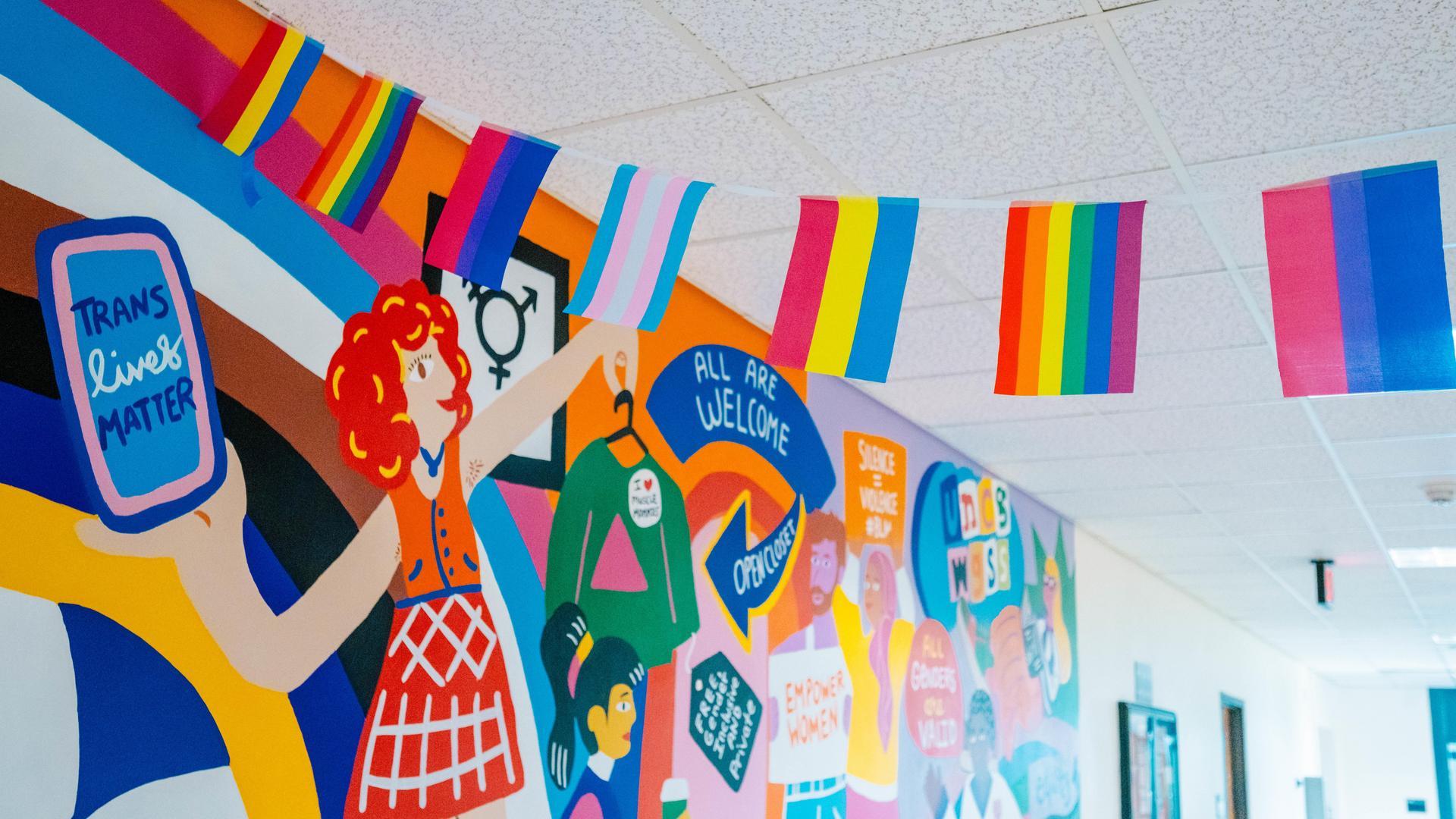 Pride flags next to UNCG's WGS mural